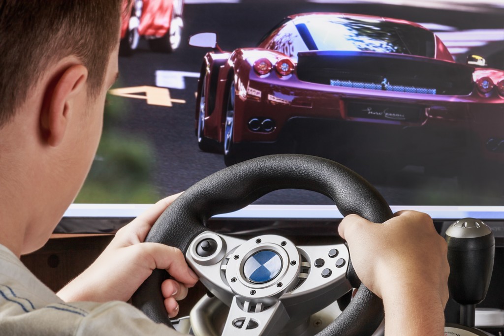 Teen playing in the race behind the wheel of a game console